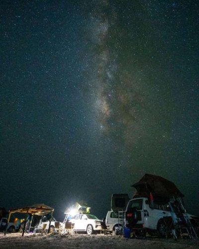 Das Camp aus Offroad Fahrzeugen unter dem sternenklaren Nachthimmel im Oman